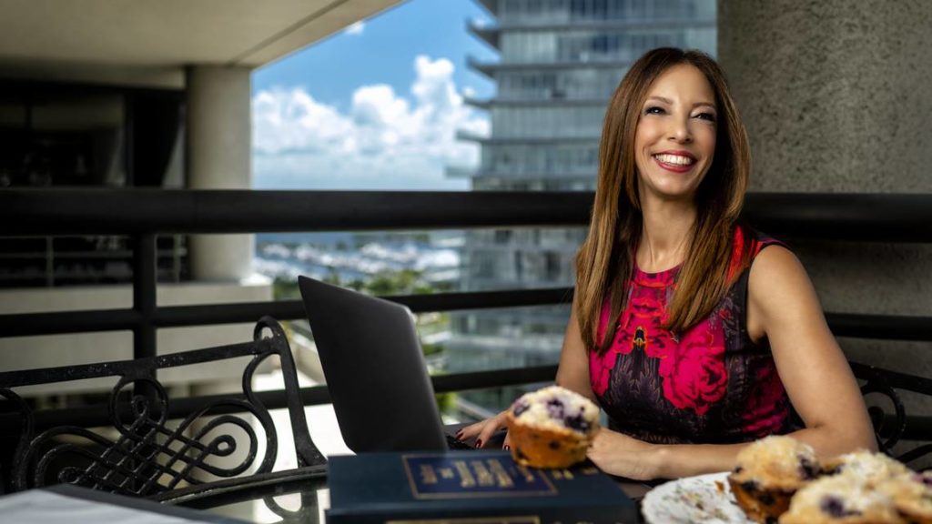 photo of Michelle Suskauer smiling at her desk in front of laptop computer